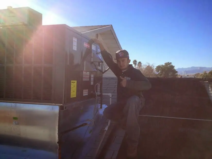 HVAC technician performing AC Tune-Up on a rooftop unit in Northridge